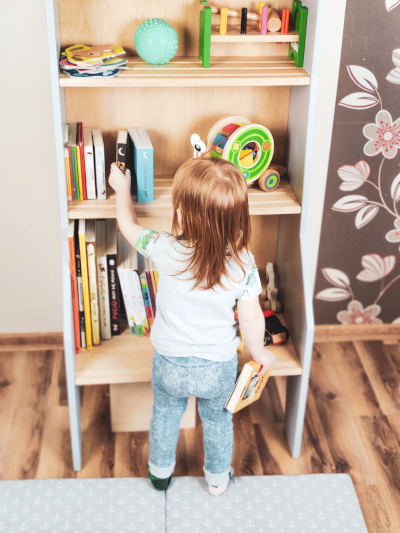 dziecko wybiera samodzielnie książki z półki w kształcie żyrafy